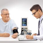 Médico revisando los signos vitales de un paciente en el monitor de signos vitales Tranquility VS de SCHILLER.