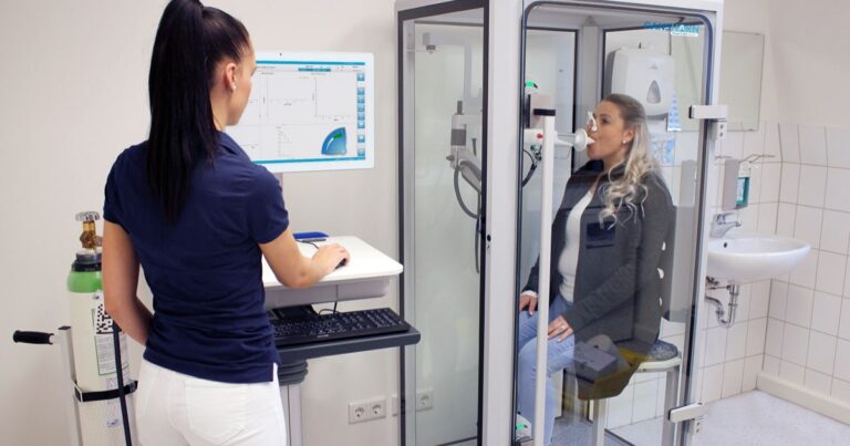 Médico realizando medición de la CRF mediante pletismografía corporal con cabina según estándares ATS/ERS.