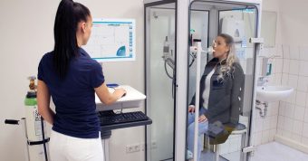 Médico realizando medición de la CRF mediante pletismografía corporal con cabina según estándares ATS/ERS.